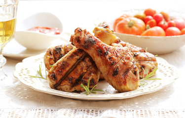 Dinner background. Grilled chicken drumsticks with rosemary.