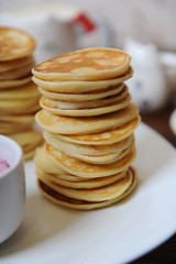 Pancakes with berry sauce on a white plate. On a wooden table closeup