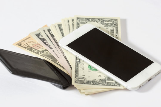 Black Leather Wallet And A Mobile Phone Left Unguarded. The Wallet Is Full Of Cash. US Dollars Coming Out Of It.