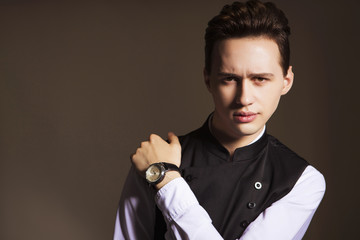 Young handsome brunette macho businessman in black suit and white shirt. neutral background