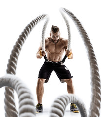 Attractive muscular man working out with heavy ropes. Photo of handsome man in sportswear isolated...