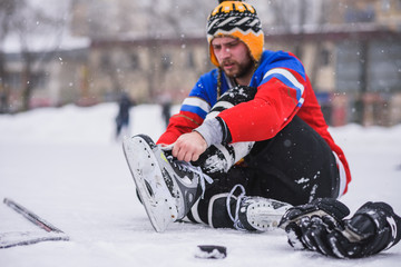 hockey player sitting on the ice to tie shoelaces