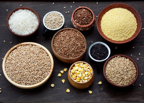 assortment of different cereals and seeds in bowl: wheat, oats, barley, rice, millet, buckwheat, corn.