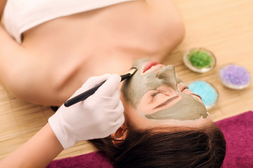 Obraz na płótnie Canvas beauty and spa concept - happy woman in spa salon lying on the massage desk