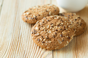 Few oatmeal cookies with seeds on a wooden table.