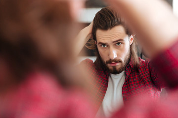 Man in plaid shirt standing and looking at the mirror