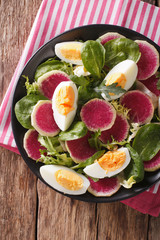 salad of watermelon radishes, eggs, spinach and lettuce mix close-up. vertical top view