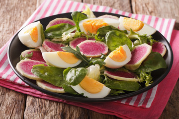 Spring salad of watermelon radishes, eggs, spinach and arugula close-up. horizontal