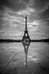 View of the Eiffel Tower from the Trocadero. Reflection tower in wet rain stone pavement. BW photography. France. Paris.