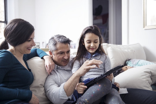 Family using tablet computer while sitting on sofa at home