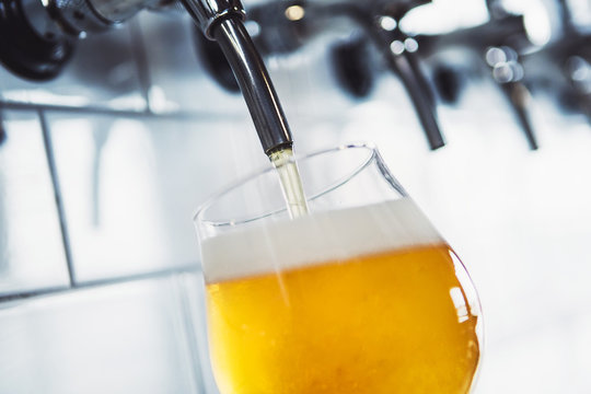 Close-up of beer filling in a glass at brewery