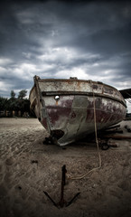 An old fishing boat on the beach. Stormy skies.