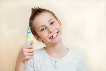 Cute boy shows his teeth and toothbrush. Light background