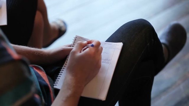 Man writing in notebook on lecture closeup