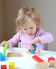 Little baby girl age of 1 years 10 months play with wooden colorful cubes