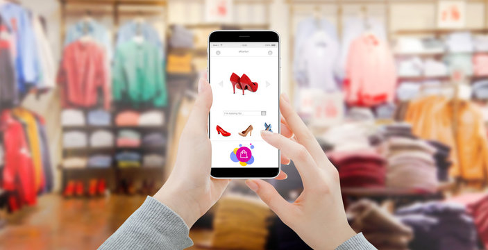 Close up of modern smartphone with shopping interface, blurred clothing store in background