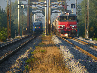 The passenger train meeting freight train on the bridge.