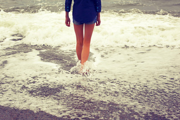 Slender legs.Girl and the sea.Photo toned in retro style.