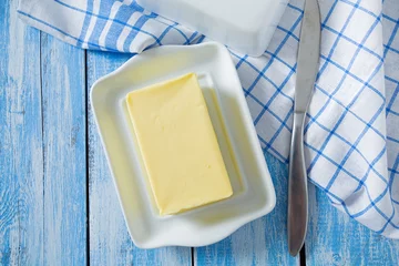 Fototapeten butter on butter dish on blue wooden surface © Diana Taliun