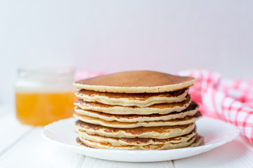 Fototapeta na wymiar Healthy breakfast. Stack of delicious, homemade pancakes with honey, cherry and banana on white plate 