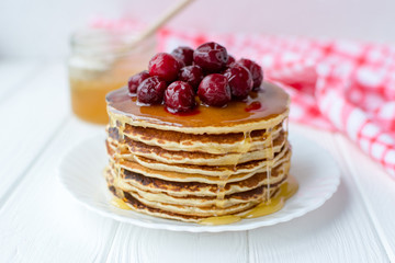 Healthy breakfast. Stack of delicious, homemade pancakes with honey and cherry on white plate 