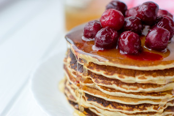 Healthy breakfast. Stack of delicious, homemade pancakes with honey and cherry on white plate 