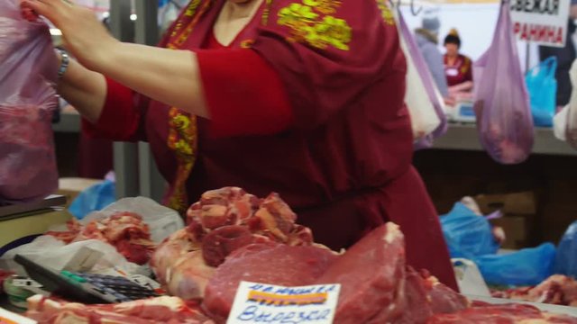 Showcase meat products in a supermarket. Russian market. Meat counters. Fresh meat on a table. The woman the seller sells meat in the market