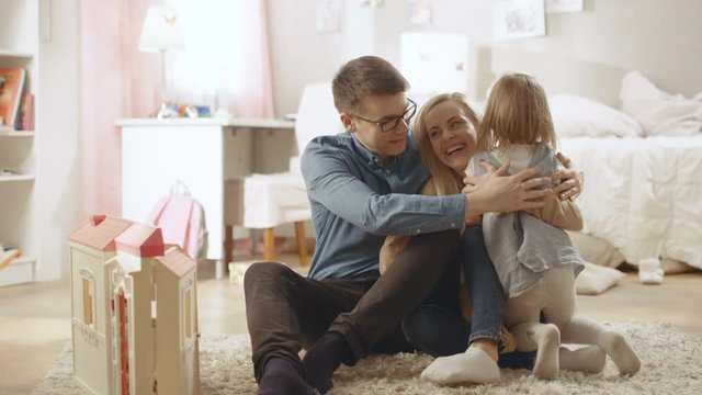 Cute Little Girl Runs Towards Her Mother and Father and They Hug Her. Children's Room is Pink, Has Drawings on the Wall and is Full of Toys. Slow Motion. Shot on RED EPIC-W 8K Helium Cinema Camera.