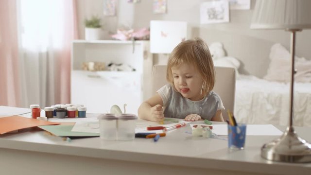 Cute Little Girl Sits at Her Table and Draws with Crayons. Her Room Is Pink, Pretty Drawings Hanging on the Walls, Many Toys Lying Around. Shot on RED EPIC-W 8K Helium Cinema Camera.