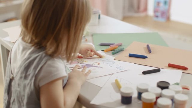 Cute Little Girl Sits at Her Table and Draws. She Paints Sun with Her Yellow Finger. Her Room Is Pink and Cosy. Shot on RED EPIC-W 8K Helium Cinema Camera.