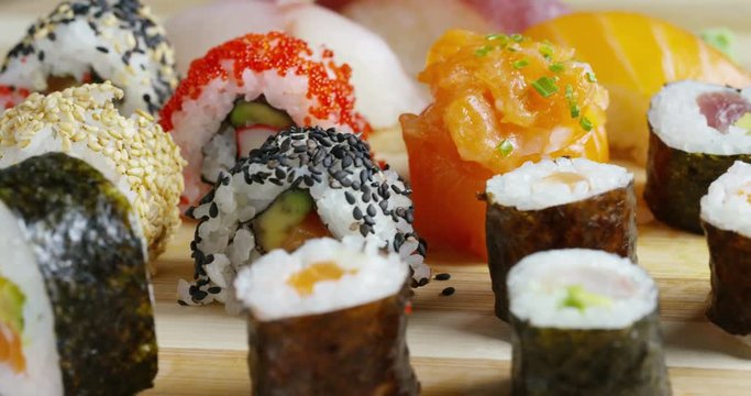 sushi,sashimi,uramaki and nighiri.typical Japanese dish consisting of rice, salmon, tuna,shrimp and fish eggs on a black background.Concept:Japanese restaurant,sushi,oriental tradition
