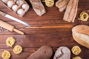 Pasta, eggs and bread on wooden background. top view with copy space. ingredients for bakery products