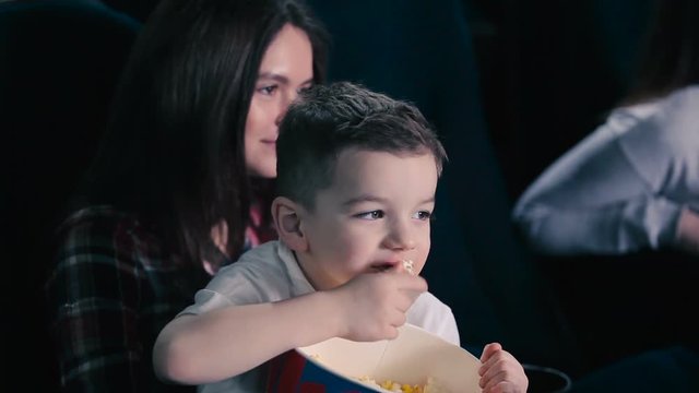 Little boy eat the popcorn in cinema