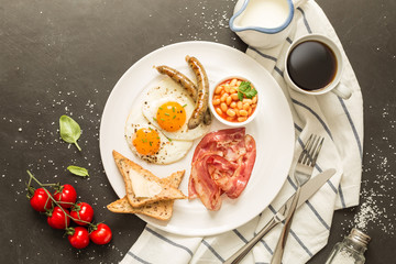 Full english breakfast on white plate, black background.