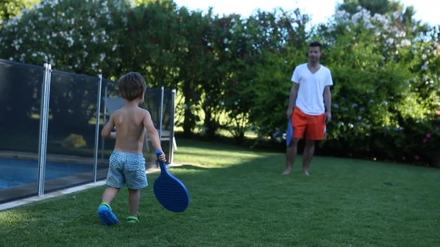 Child playing paddle ball with father. Young 5 year old boy playing ball with dad