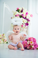 Fototapeta na wymiar Little angel smiling and happy sitting on the background of flowers and harp