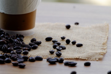 Ice coffee and coffee beans on the brown table.