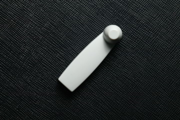 Personalized hard tags for clothing put on the dark color background represent the shop lifting...