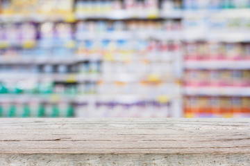 Abstract blur supermarket shelves background with wood table