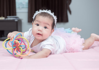 cute baby smile and play toy on pink blanket
