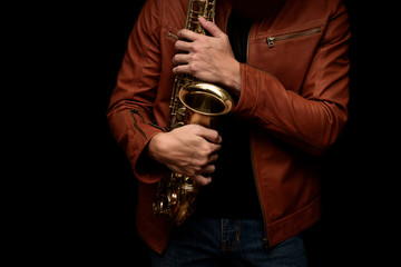 musician saxophone player holding his saxophone on isolated black background.