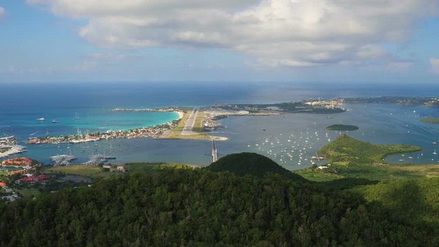 St Maartin Aerial v52 Flying low over tall hillsides sideways with views of airport and runway.