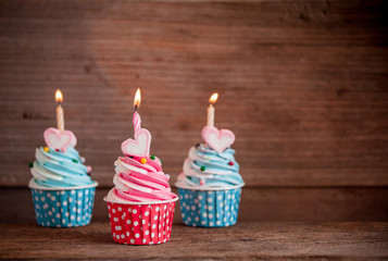 birthday cupcake with sweet heart shape of marshmallow and candle on wooden background