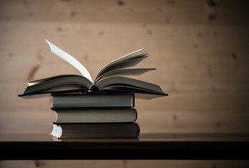 Open book, stack of hardback books on wooden table. Education concept. Copy space.