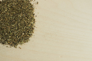 Heap of Dried Basil Flakes on Wood Background
