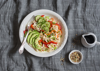 Udon noodles with quick pickled vegetables and avocado on a gray table, top view. Healthy vegetarian food concept