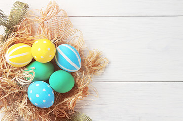 Easter eggs in the nest on white wooden background