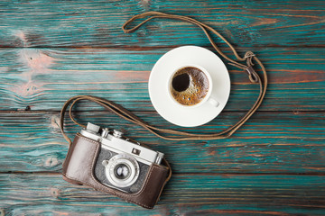 Vintage camera and cup of coffee on rustic wooden background