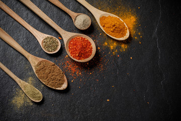 Herbs and spices and the spoon over black stone background. Top view