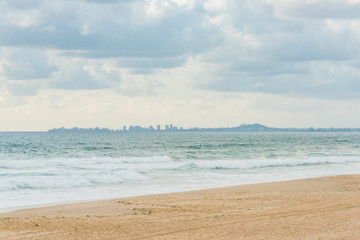 Fototapeta na wymiar Surfers Paradise beach with distant cityscape on the horizon